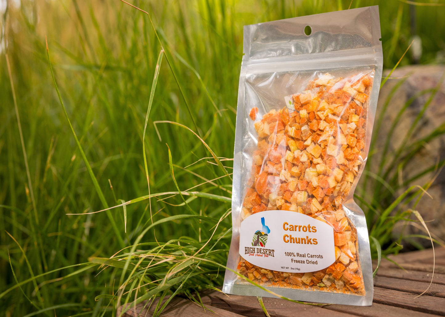 Package of 'Carrots Chunks' pet food on a wooden surface with grass in the background