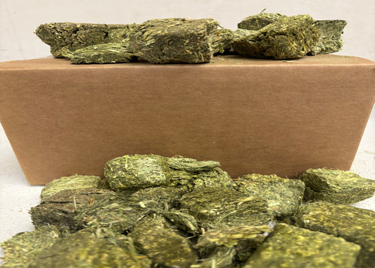 Alfalfa cubes on a brown rectangular block against a white background