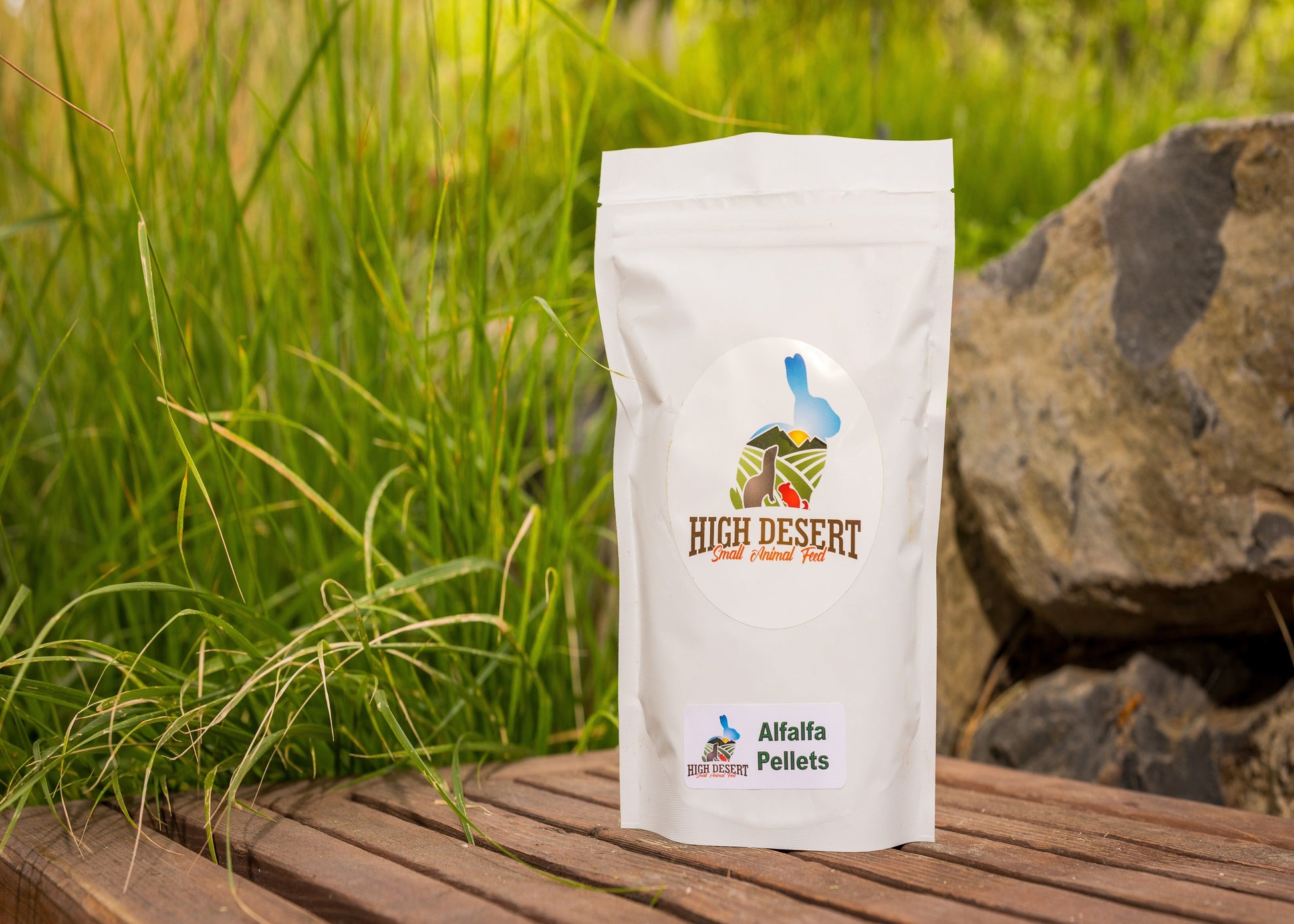 High Desert Alfalfa Pellets package on a wooden surface with grass and rocks in the background