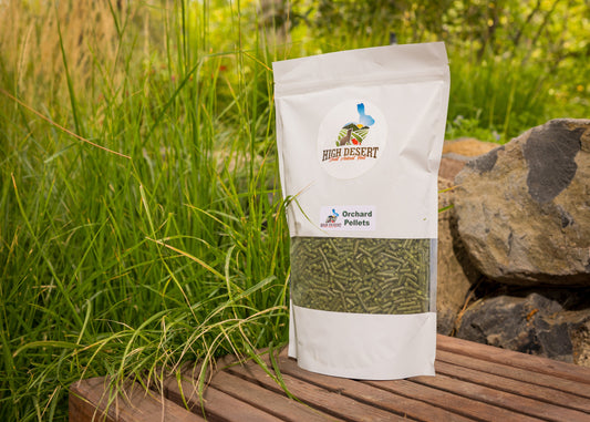 Bag of High Desert Pellets on a wooden surface with grass and rocks in the background