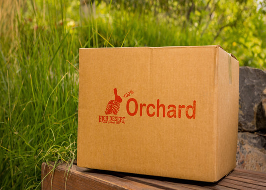 Box of 'High Desert Orchard' logo on a wooden surface with grass in the background