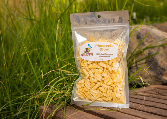Package of pineapple slices on a wooden surface with grass in the background