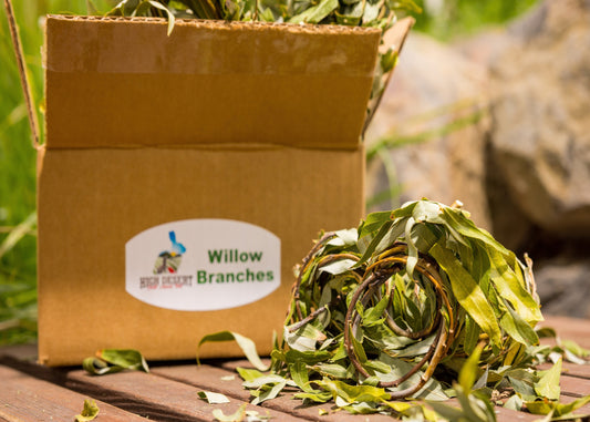 Box of Willow Branches with a visible brand label on a wooden surface with greenery in the background.